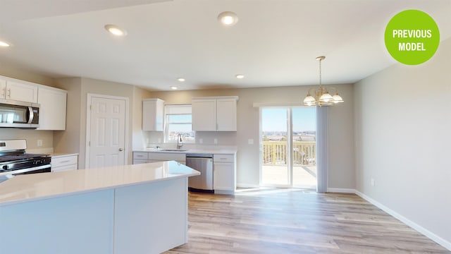 kitchen with appliances with stainless steel finishes, a chandelier, decorative light fixtures, white cabinetry, and light wood-type flooring