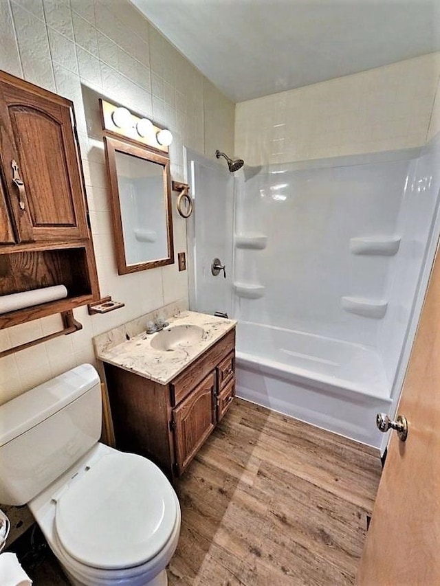 810 2nd Ave, Kenmare, ND 58746 - full bathroom featuring shower / tub combination, tile walls, toilet, and wood-type flooring