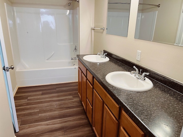 bathroom featuring vanity with extensive cabinet space, tub / shower combination, hardwood / wood-style flooring, and dual sinks