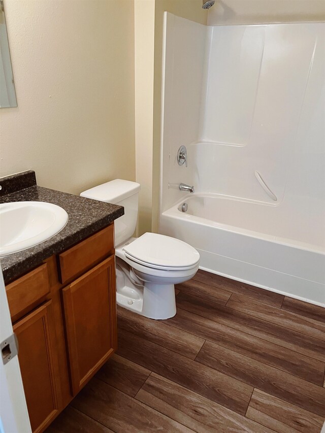 full bathroom featuring hardwood / wood-style floors, shower / tub combination, vanity, and toilet