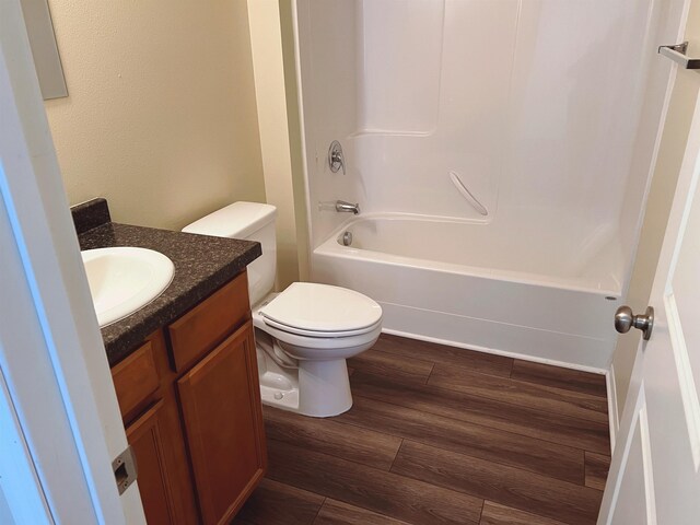 full bathroom with bathtub / shower combination, vanity, hardwood / wood-style flooring, and toilet