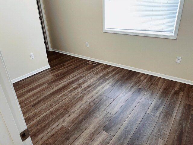 unfurnished room featuring a wealth of natural light and dark hardwood / wood-style floors