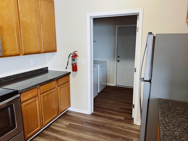 kitchen with appliances with stainless steel finishes, dark hardwood / wood-style flooring, and washing machine and clothes dryer