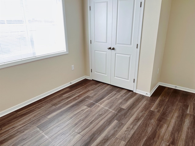 unfurnished bedroom featuring a closet and dark wood-type flooring