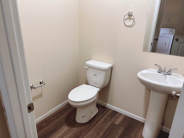 bathroom featuring wood-type flooring, toilet, and washer / clothes dryer