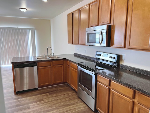 kitchen featuring sink, stainless steel appliances, light hardwood / wood-style floors, and kitchen peninsula