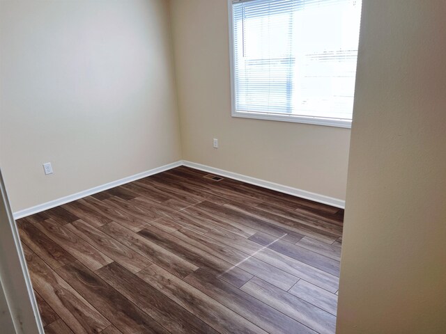 spare room featuring a wealth of natural light and dark hardwood / wood-style floors