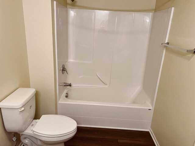 bathroom with hardwood / wood-style floors, shower / washtub combination, and toilet