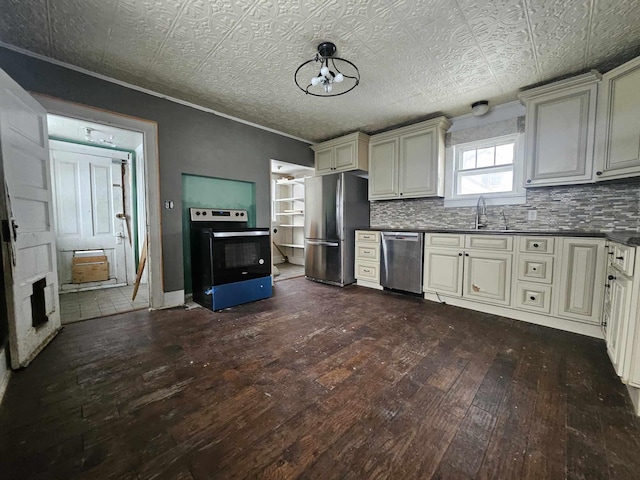 kitchen featuring cream cabinetry, hardwood / wood-style floors, stainless steel appliances, decorative backsplash, and sink