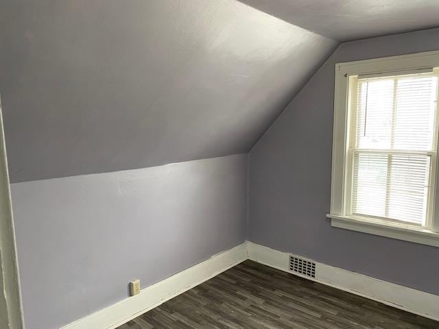 additional living space featuring dark wood-type flooring and vaulted ceiling