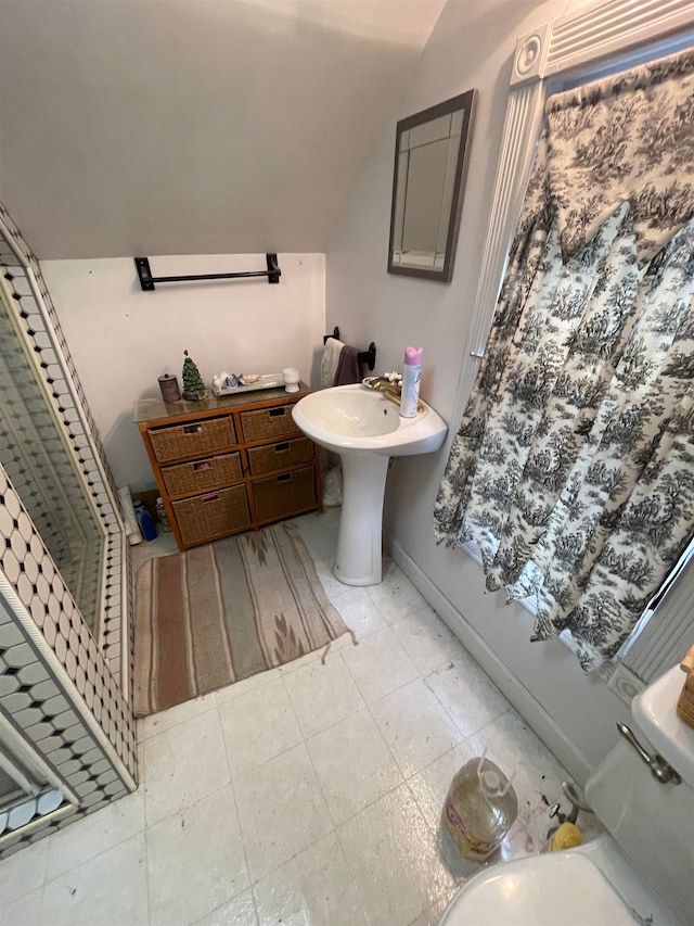 bathroom with tile flooring, toilet, and lofted ceiling