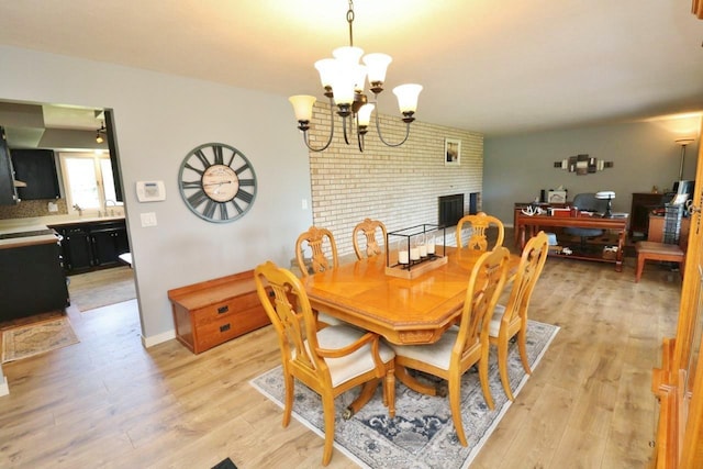 dining space with a fireplace, light hardwood / wood-style flooring, and a notable chandelier