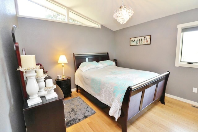 bedroom featuring a notable chandelier, lofted ceiling, and light hardwood / wood-style flooring