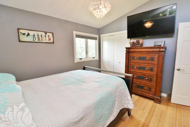 bedroom with light hardwood / wood-style floors, lofted ceiling, and a notable chandelier