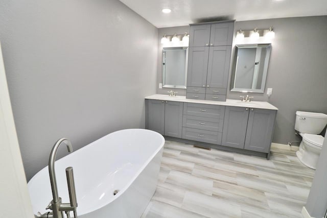 bathroom featuring a bath, vanity, and toilet