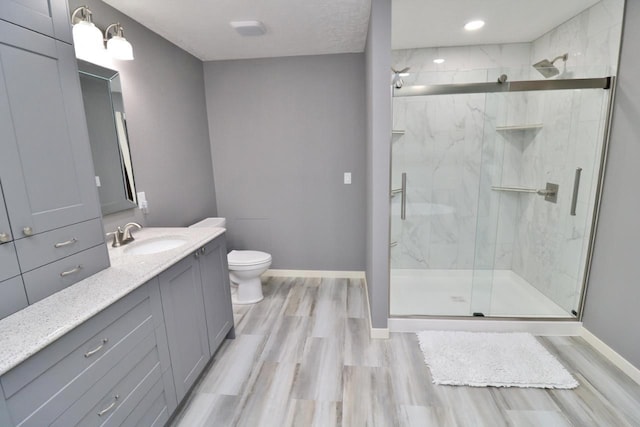 bathroom featuring wood-type flooring, vanity, toilet, and walk in shower