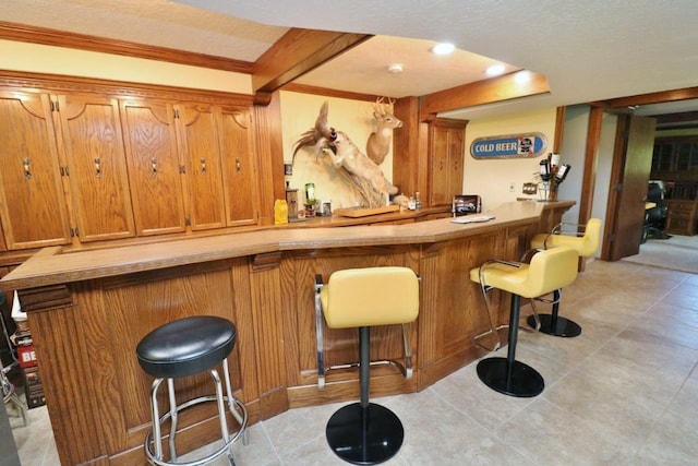 bar featuring ornamental molding, a textured ceiling, and light tile patterned floors