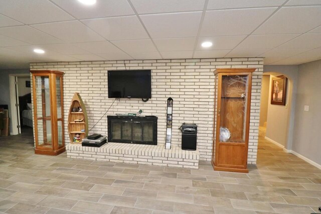 living room with a paneled ceiling and a brick fireplace