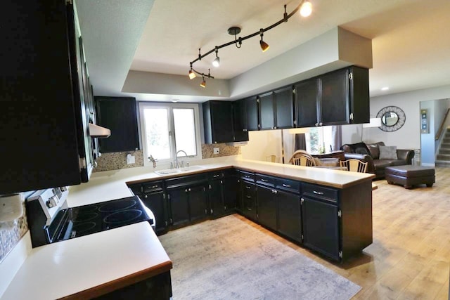 kitchen with kitchen peninsula, tasteful backsplash, sink, light hardwood / wood-style flooring, and white electric stove