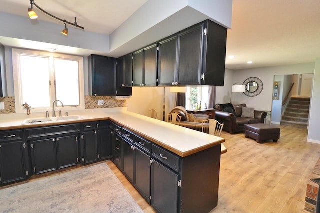 kitchen featuring kitchen peninsula, tasteful backsplash, light hardwood / wood-style floors, and sink