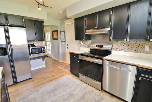 kitchen with backsplash, rail lighting, light wood-type flooring, and appliances with stainless steel finishes