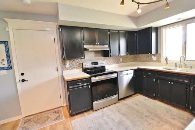 kitchen with backsplash, sink, stainless steel appliances, and light hardwood / wood-style floors