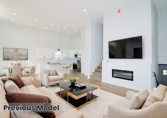 living room featuring sink, a high ceiling, and light wood-type flooring