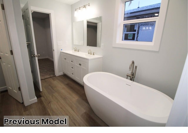 bathroom with vanity, wood-type flooring, and a bath