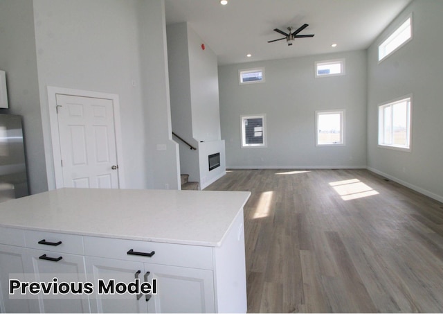 unfurnished living room with a high ceiling, light hardwood / wood-style flooring, and ceiling fan