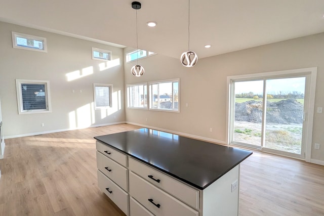 kitchen featuring a center island, white cabinetry, light hardwood / wood-style flooring, and decorative light fixtures