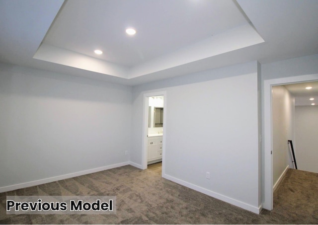 carpeted empty room with a tray ceiling