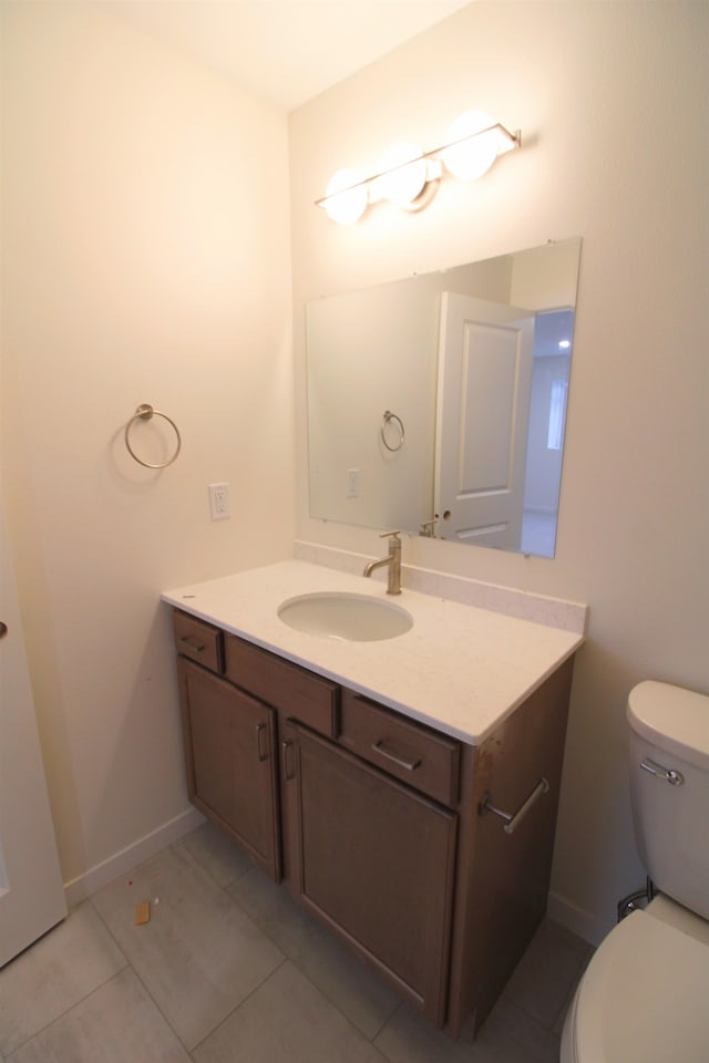 bathroom with toilet, vanity, and tile patterned flooring