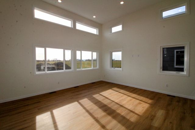 unfurnished room featuring a towering ceiling and hardwood / wood-style flooring