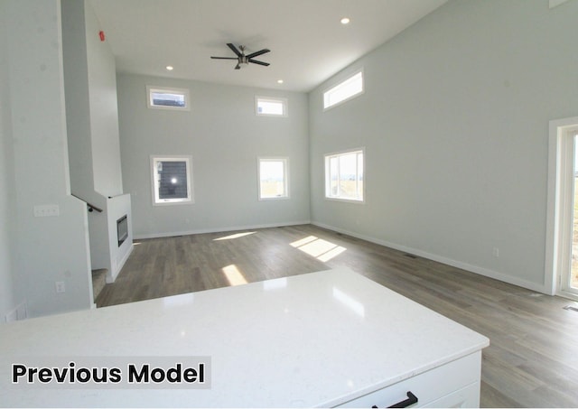 living room featuring light hardwood / wood-style floors, a high ceiling, and ceiling fan