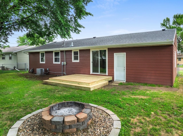 rear view of house with a fire pit, cooling unit, a wooden deck, and a lawn