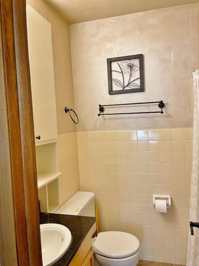 bathroom with toilet, tile walls, and vanity