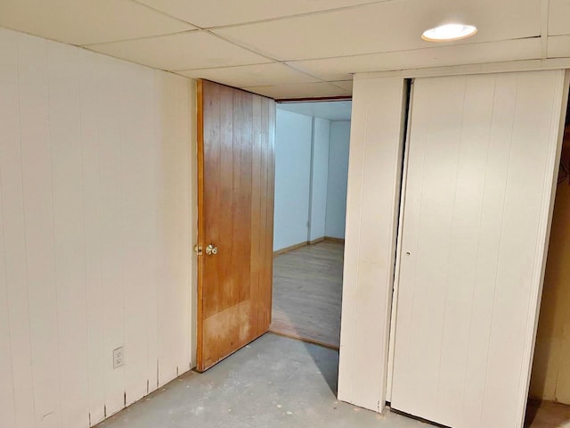 interior space featuring a drop ceiling, a closet, and wooden walls