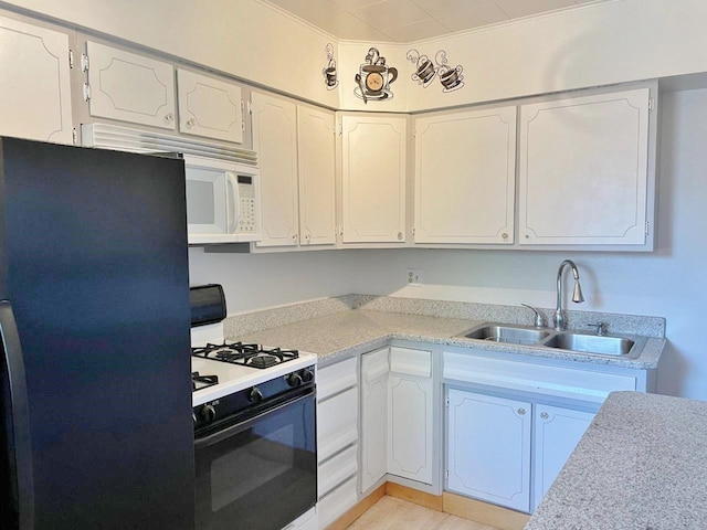 kitchen with black refrigerator, white cabinetry, range with gas cooktop, and sink