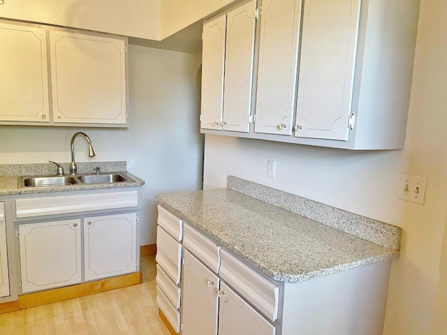 kitchen with sink, white cabinetry, and light hardwood / wood-style flooring