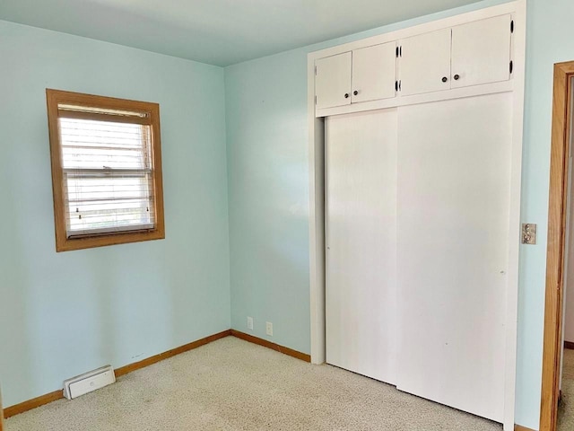 unfurnished bedroom featuring light colored carpet and a closet