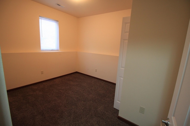 spare room with dark carpet