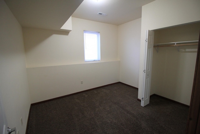 unfurnished bedroom featuring a closet and dark colored carpet