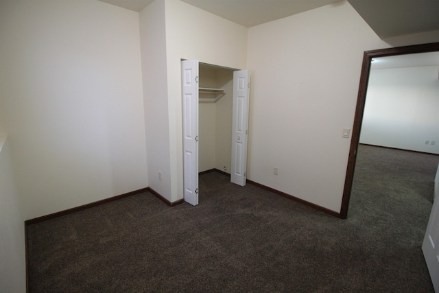 unfurnished bedroom with a closet and dark carpet