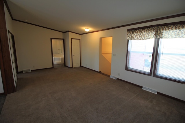 spare room featuring vaulted ceiling, dark carpet, and crown molding