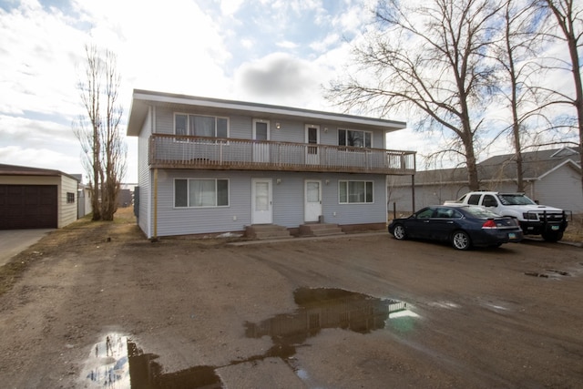 view of front of property with a balcony, a garage, and an outdoor structure