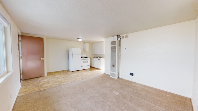 unfurnished living room with sink, a textured ceiling, and light colored carpet