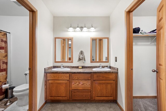 bathroom featuring dual vanity and toilet