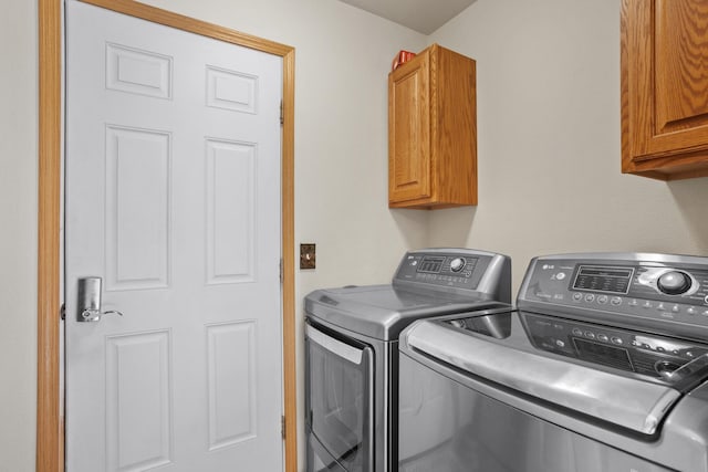 washroom with washing machine and dryer and cabinets