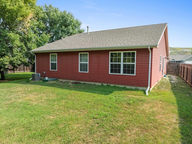 back of house featuring central AC unit and a lawn