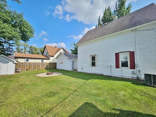 401 5th St, Rugby, ND 58368 - view of yard with an outdoor structure, central AC, a fenced backyard, a shed, and an outdoor fire pit